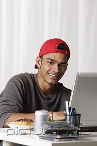 PictureIndia - young man with red cap working on laptop at desk