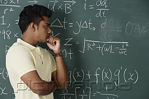 PictureIndia - young man standing in front of chalkboard, thinking