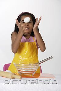 PictureIndia - Girl baking, tossing egg