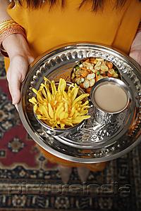 PictureIndia - tight shot of a woman holding a tray of tea and snacks