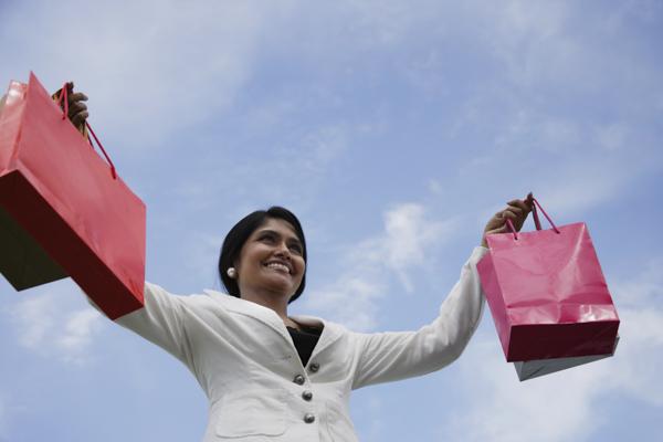 PictureIndia - Indian woman smiling and holding up shopping bags.