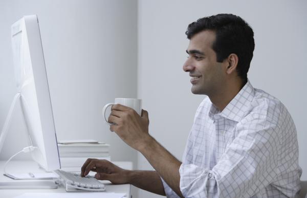 PictureIndia - Indian man working on computer and drinking coffee