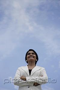 PictureIndia - Indian woman smiling and looking up with blue sky background
