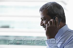 PictureIndia - Head shot of mature Indian man talking on phone