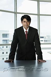 PictureIndia - Indian businessman standing behind desk