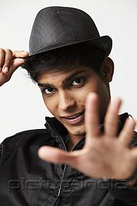 PictureIndia - head shot of young man wearing a hat with hand outstretched