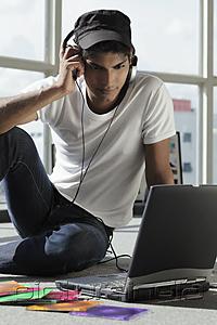 PictureIndia - young man listening to music while looking at laptop