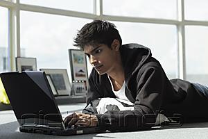 PictureIndia - young man laying on floor with laptop