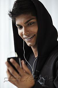 PictureIndia - Head shot of young man wearing hooded sweat shoot and listening to music