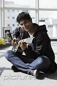 PictureIndia - young man sitting on ground playing a guitar