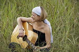 Mind Body Soul - young woman playing guitar in field