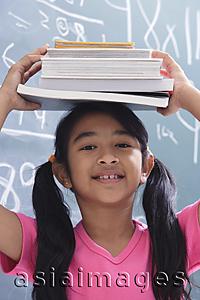 Asia Images Group - girl with books stacked on head