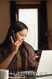 Asia Images Group - smiling woman working at laptop on phone