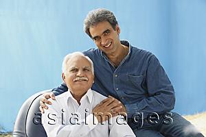 Asia Images Group - Senior man in chair, adult son behind, clasped hands