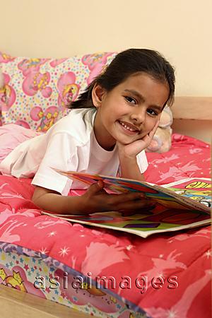 Asia Images Group - Girl reading book in bed