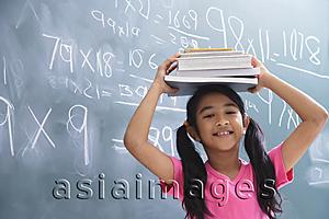 Asia Images Group - girl with books stacked on head