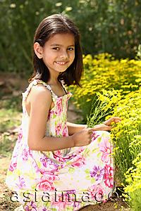 Asia Images Group - Little girl kneeling by yellow flowers
