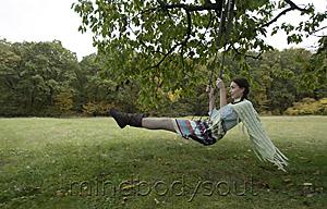 Mind Body Soul - young woman swinging on tree swing