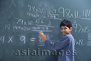 Asia Images Group - boy working at chalkboard, smiling at camera