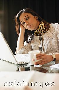 Asia Images Group - business woman working at laptop, coffee in hand