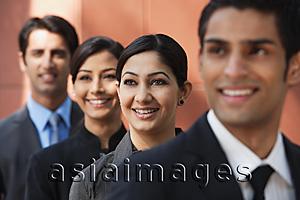 Asia Images Group - businessman in foreground, three colleagues in background, all smiling