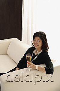 AsiaPix - elegant woman sitting on couch with glass of champagne