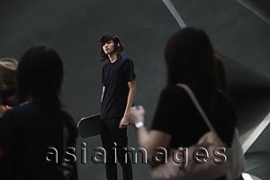 Asia Images Group - youth holding skateboard, in crowd