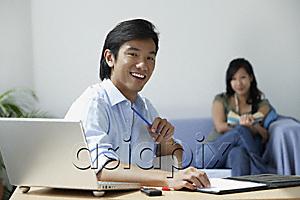 AsiaPix - Young couple at home; man at desk, woman with book on couch