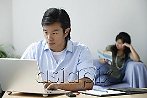AsiaPix - Young couple at home; man on computer, woman reading