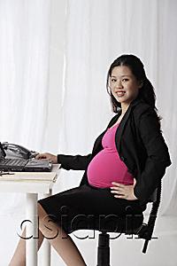AsiaPix - Profile of pregnant businesswoman at desk