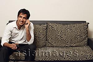 Asia Images Group - man sitting on couch talking on phone