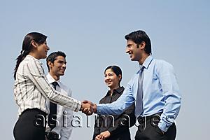 Asia Images Group - four business colleagues, two shaking hands