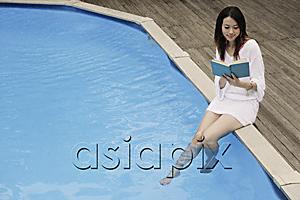 AsiaPix - Young woman reading poolside