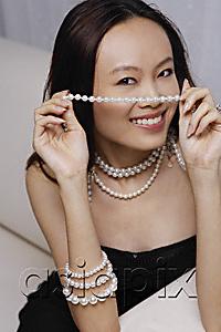 AsiaPix - Young woman holding strand of pearls