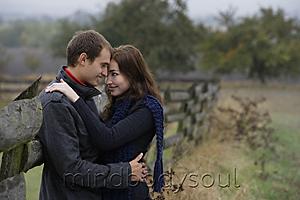 Mind Body Soul - Young couple embracing against country fence