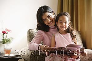 Asia Images Group - little girl sits on mother's lap, both smile at camera