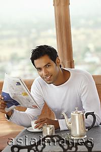 Asia Images Group - man reading morning newspaper, having hot drink