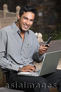 Asia Images Group - man with phone and laptop computer