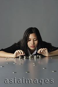 Asia Images Group - young lady sitting counting coins
