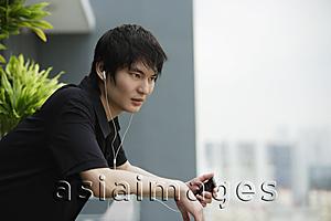 Asia Images Group - young man listening to MP3, on balcony