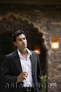 Asia Images Group - young man in suit with glass of wine in hand