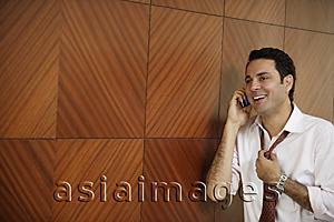 Asia Images Group - businessman on cell phone, loosening tie