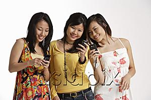 AsiaPix - Three women looking at hand phones.