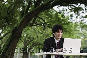 Asia Images Group - young man in suit, using laptop outdoors