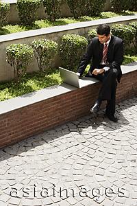 Asia Images Group - businessman working on laptop outside