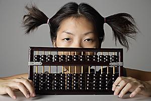 AsiaPix - Young woman peering behind abacus.