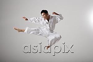 AsiaPix - Man doing a flying kick, martial arts