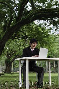 Asia Images Group - young man in suit, using laptop at a park