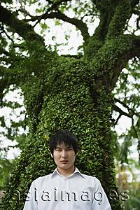 Asia Images Group - young man standing in front of tree