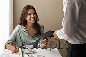 AsiaPix - Young woman paying the check at a restaurant